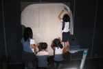 아이들이 라이트에 의지한 채 벽면에 커다랗게 글자를 쓰고 있는 모습이다