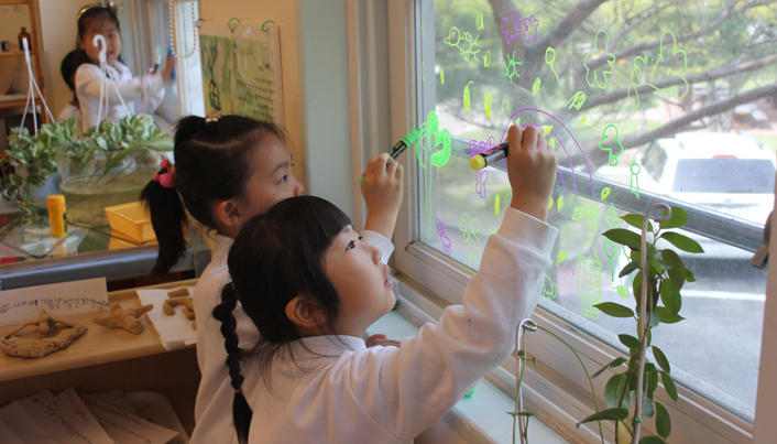 연두색 펜과 보라색 펜을 이용해 창문에 그림을 그리고 있는 아이들의 모습이다