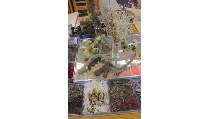 여러 종류의 꽃과 솔방울 등 다양한 식물이 책상 위에 놓여져있다