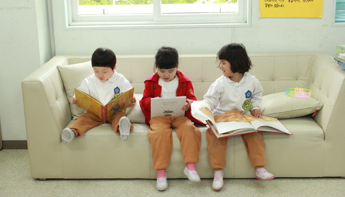 아이들 셋이 소파에 앉아 각자 골라든 책을 읽고 있다