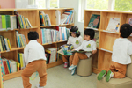 아이들이 도서실에 비치된 작은 소파들 위에 앉아 책을 읽거나 책장에 꽂힌 책들을 보고 있다