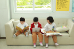 아이들 셋이 소파에 앉아 각자 골라든 책을 읽고 있다