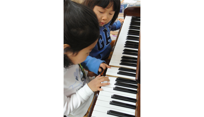 두 여자아이가 함께 앉아 피아노를 치고 있는 모습이다
