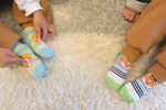 뽀로로 양말을 신은 두 아이가 발을 카펫 위에 올려놓고 있다